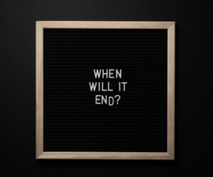 From above of chalkboard with When Will It End inscription on black background
