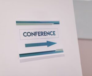 Close-up of a conference directional sign indoors, guiding participants.