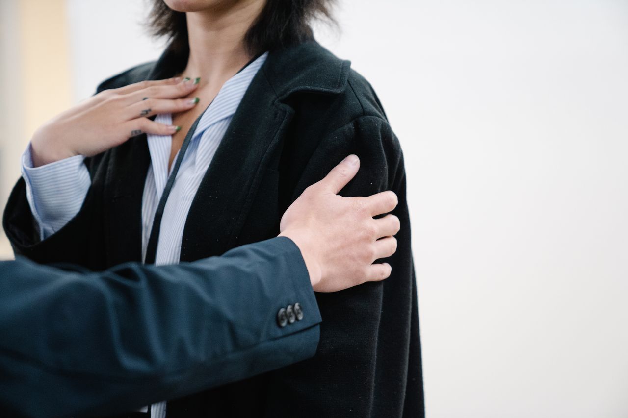 Detailed close-up image showing a person in a black blazer with hands gesturing on chest. Great for business and lifestyle themes.