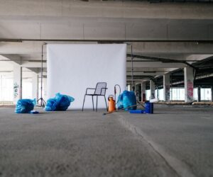 A minimalist scene featuring a chair with a white backdrop in an industrial space.