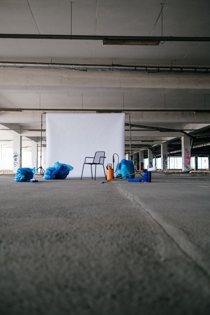 A minimalist scene featuring a chair with a white backdrop in an industrial space.